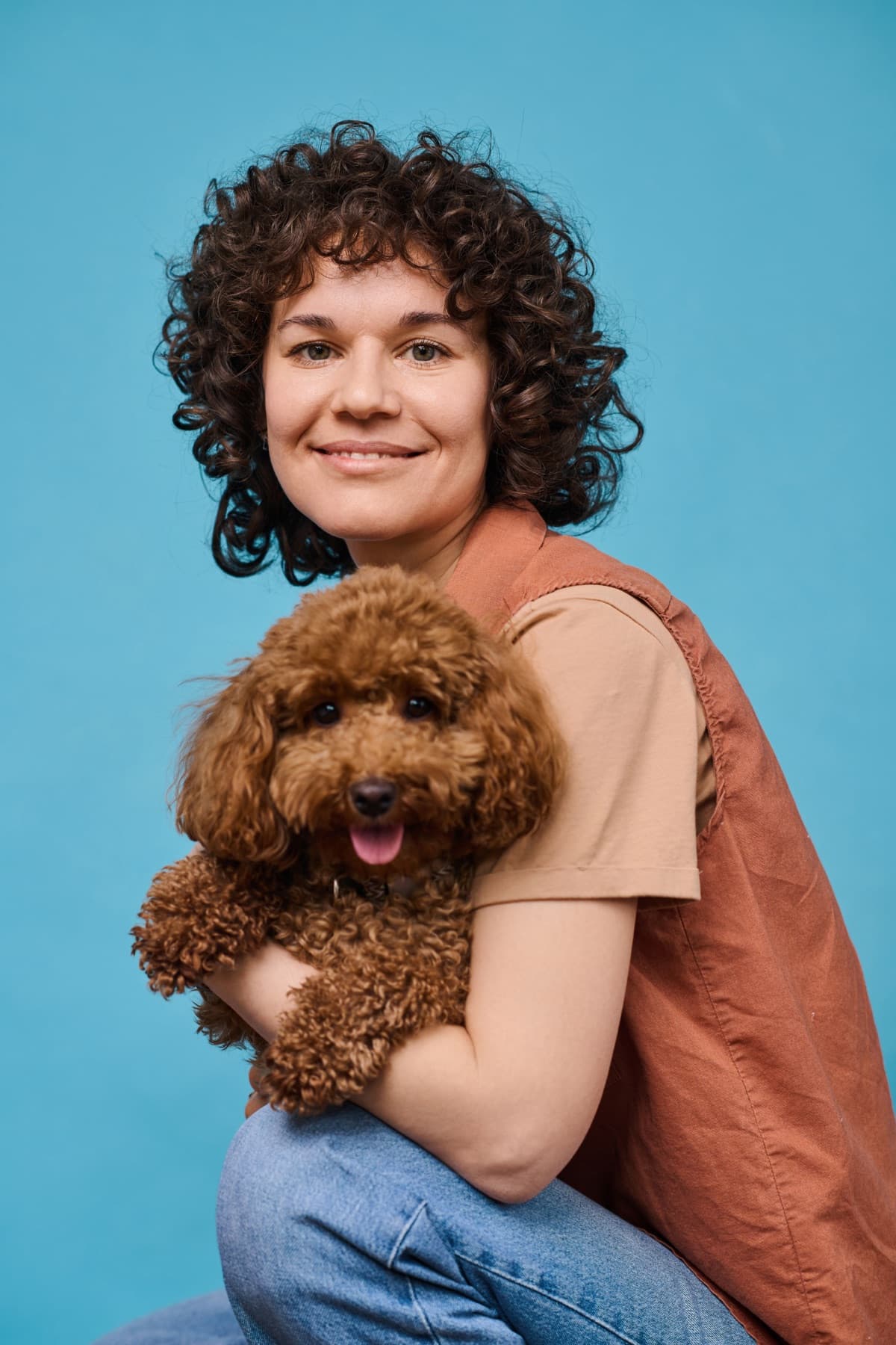 Una mujer sonríe abrazando a su perro poodle