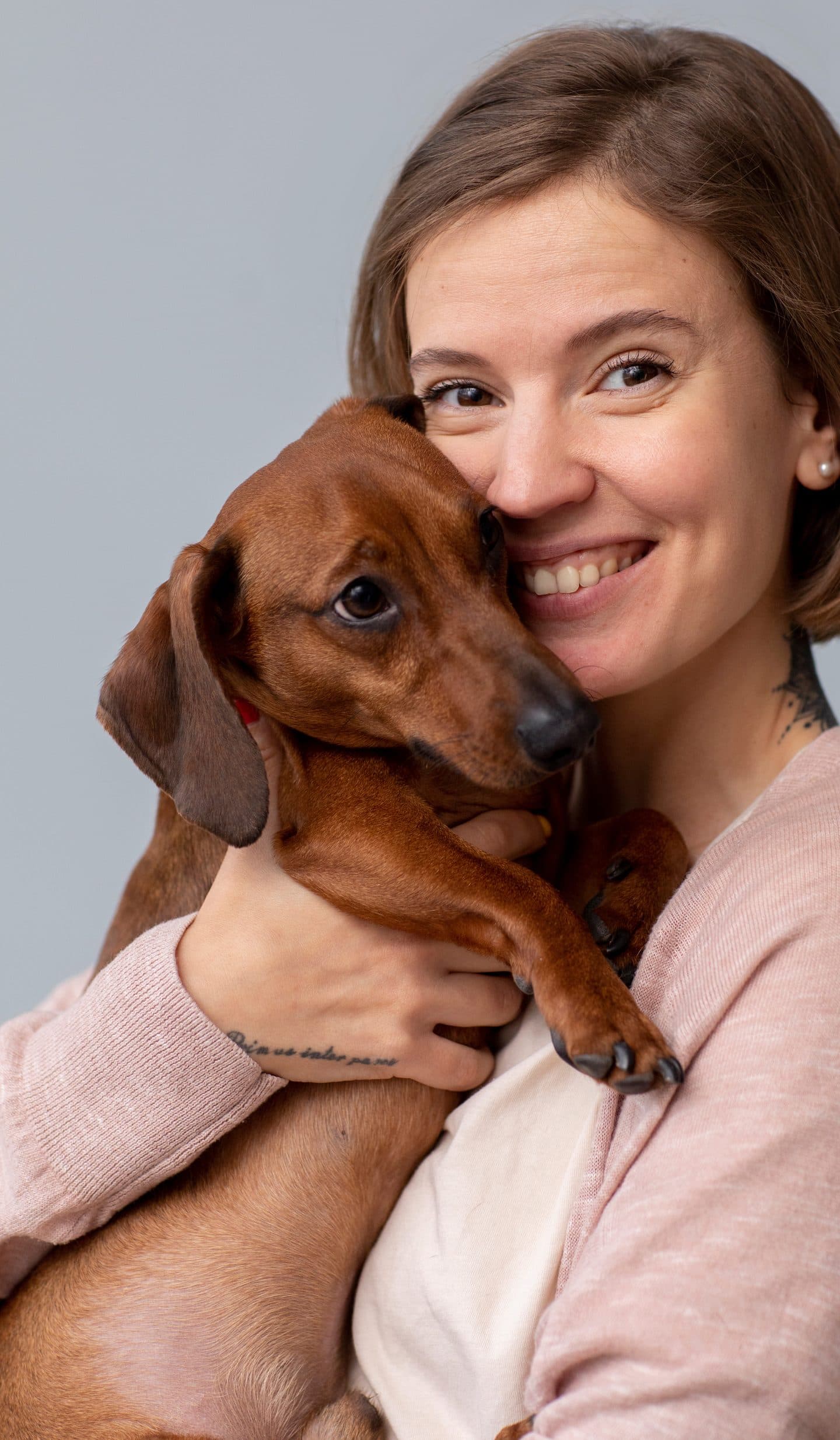 Una mujer sonríe abrazando a su perro salchicha
